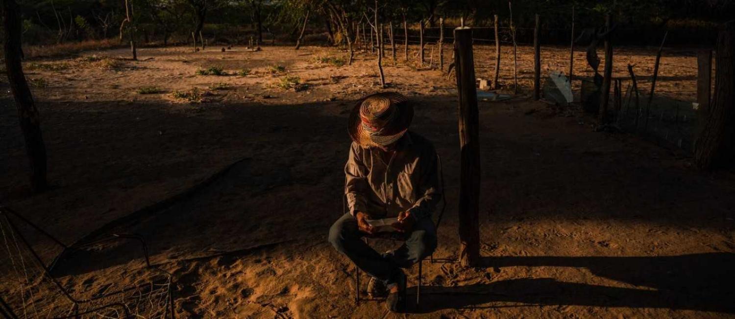 Jos&eacute; Manuel Gonzalez, venezuelano sentado em frente a uma cova com seus dois filhos enterrados em meio ao caos das guerrilhas.